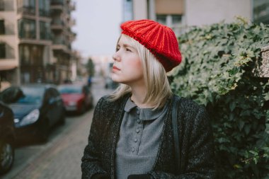 Sokakta yürüyen kırmızı bereli genç bir kadın.