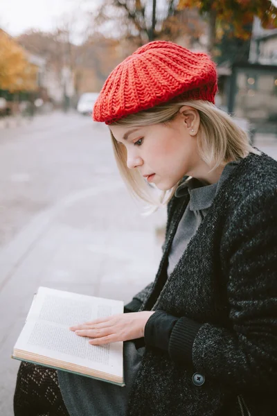 Young exchange student reading a book in the old town. European woman with red beret reading outdoors.