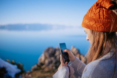 Genç bir kadın kışın gölün fotoğraflarını çekiyor.