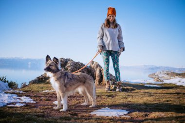 Kışın bir gölde köpeğini gezdiren kadın.