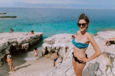 Kadın güneşleniyor ve sahilde poz veriyor.