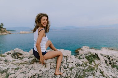 Kadın güneşleniyor ve sahilde poz veriyor.