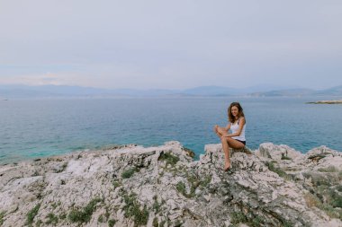 Kadın güneşleniyor ve sahilde poz veriyor.