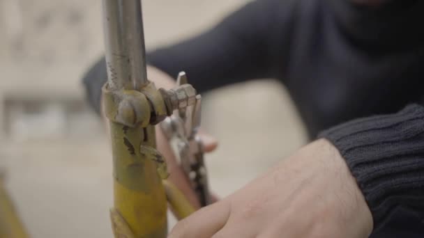 Muž se snaží uvolnit šroub na kole — Stock video