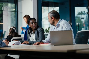 Çağdaş bir çalışma alanında kurumsal bir toplantı sırasında çeşitli iş adamları tartışır.