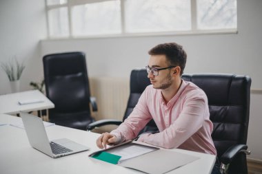 Genç adam ofiste bir proje üzerinde çalışıyor.