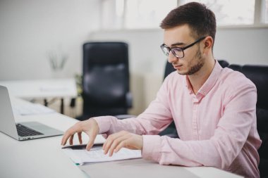 Genç adam ofiste bir proje üzerinde çalışıyor.