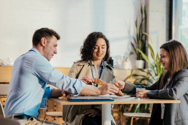 İş arkadaşları kahve molası verip börek yiyip sohbet ediyorlar.