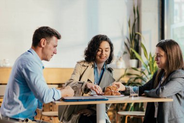 İş adamları kahve molası veriyor, yemek paylaşıyor ve kafe ortamında sohbet ediyorlar.