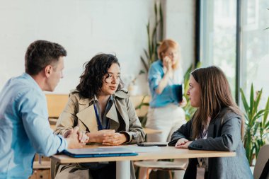 İş arkadaşları, modern bir uzay kafe 'sinde bir masada tartışıyorlar.
