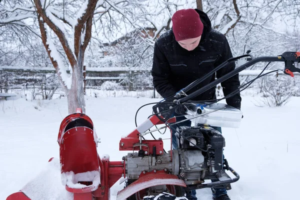 man cleans snow with snow blower