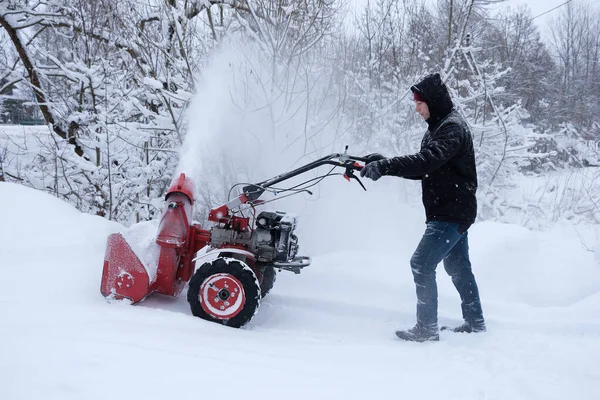 man clearing snow in backyard with snow blower
