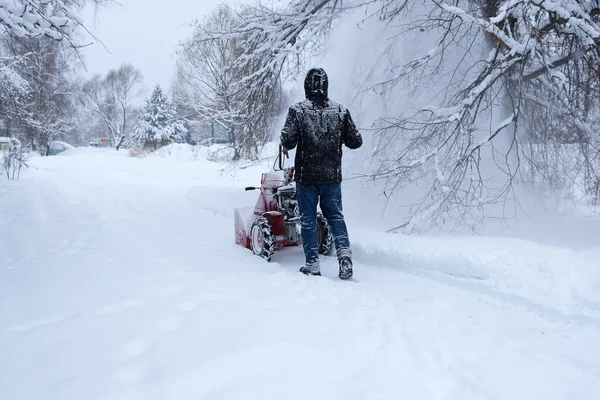 man clearing snow in backyard with snow blower