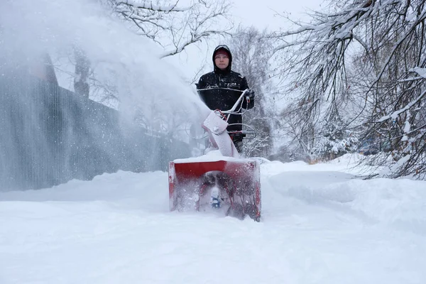 man clearing snow in backyard with snow blower