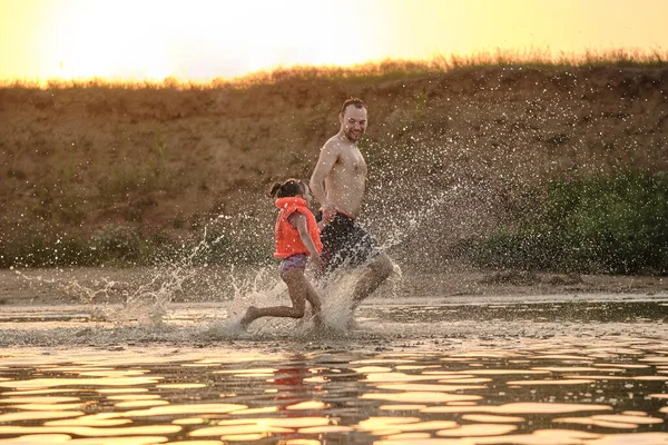 father playing with his daughter in the water while on vacation