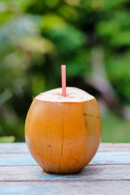 Tahta masada kırmızı pipetli taze hindistan cevizi içilmeye hazır..