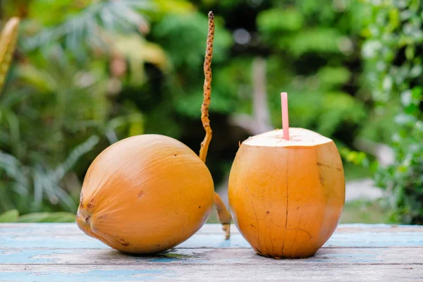 新鲜的椰子 红色的稻草放在木制桌子上 随时可以饮用 — 图库照片