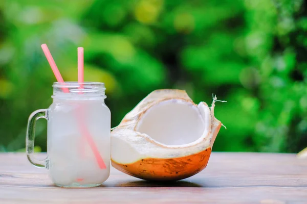 若いココナッツと新鮮なココナッツは 木製のテーブルの上にガラスの中で飲む — ストック写真