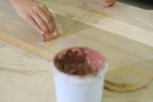 İş kıyafetleri ve yüz maskesi takan genç marangoz konsol masasında ahşap dolgu malzemesi kullanıyor. .