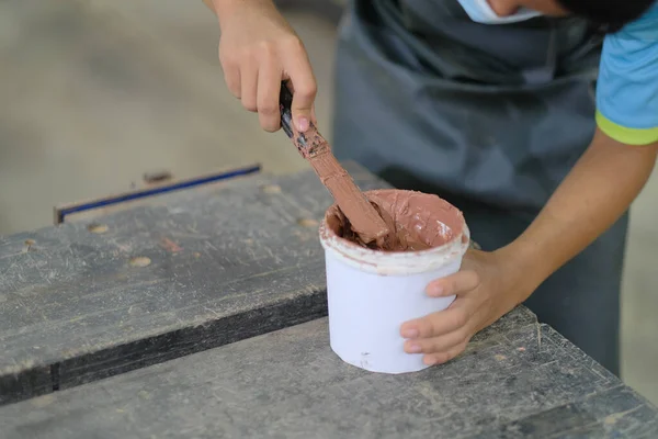 İş kıyafetleri ve yüz maskesi takan genç marangoz konsol masasında ahşap dolgu malzemesi kullanıyor. .
