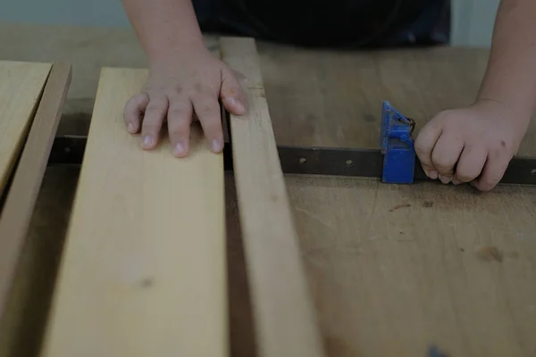 Carpenter joining pieces of wood with long bar clamp and glue