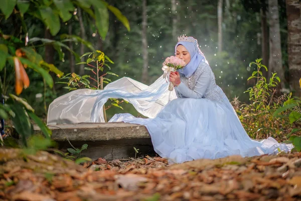 Düğün fotoğrafı çekimi. Gelin ve damat bebek mavisi giyiyor Ormanda geleneksel Malezya giysisi.