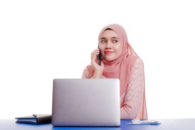 Bilgisayarla çalışan mutlu gülümseyen Asyalı Müslüman kadın portresi ve beyaz arka planda izole edilmiş akıllı telefon. Modern yaşam tarzı kavramı.