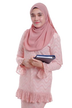 Başörtüsü takmış, gülümseyen ve kitap tutan oldukça modern bir Asyalı kadın..