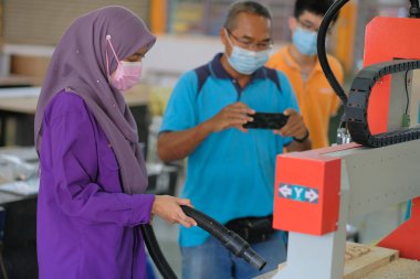 Muadzam Shah , Malaysia - November 19th ,2020 : Woman is  running the CNC machine. Device with numerical control in woodwork workshop.