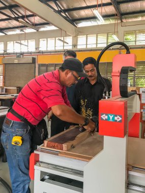 Muadzam Shah , Malaysia - November 19th ,2020 : Man is running the CNC machine. Device with numerical control in woodwork workshop. clipart