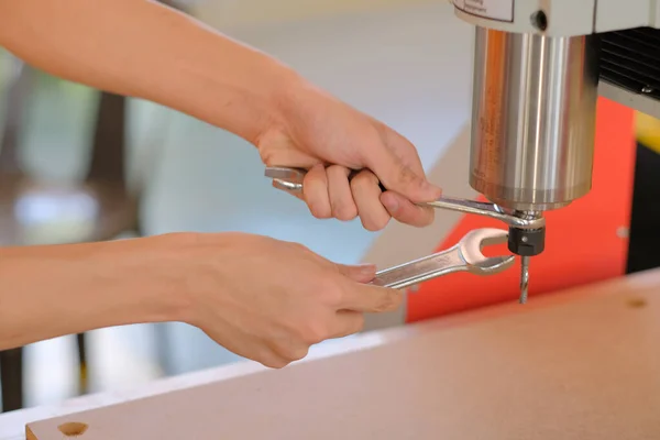 Atölyedeki CNC yönlendiricisini değiştirmek için anahtarı kullanan teknisyen.