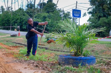 Muadzam Şah, Malezya - 22 Kasım 2020: Bölge sakinleri göl kenarını temizlemek ve temizlemek için birbirlerine takım çalışması ruhuyla yardım ediyorlar. İnsanlar peyzaj işleri yapıyor. .