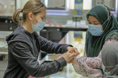 Kuantan, Malezya - 5 Aralık 2020: Kuyumcuda altın bilezik deneyen kadın.