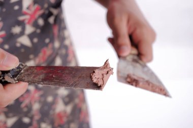 Genç marangoz, beyaz arka planda izole edilmiş kanepe sunucusu projesini bitirmek için kazıyıcı ve ahşap dolgu malzemesi kullanıyor.