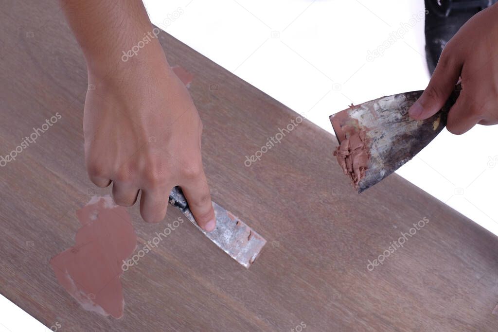 Young carpenter in work clothes  using scraper and wood filler in finishing work  for sofa server project isolated on white background