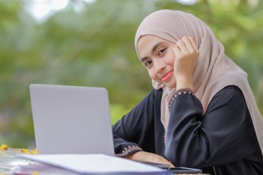 Güzel İslami kız öğrencinin başörtüsü taktığı fotoğraf gümüş dizüstü bilgisayar kullanıyor..