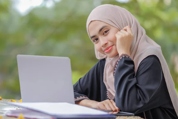 Güzel İslami kız öğrencinin başörtüsü taktığı fotoğraf gümüş dizüstü bilgisayar kullanıyor..