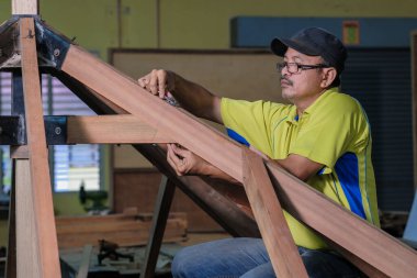 Marangoz yeni bir teras inşaatında çatı kirişlerini sürgülemek için somun ve cıvata kullanıyor. .