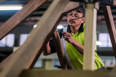 Marangoz yeni bir teras inşaatında çatı kirişlerini sürgülemek için somun ve cıvata kullanıyor. .