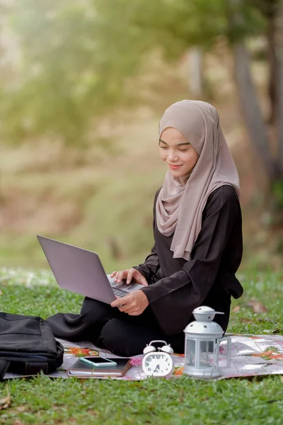 美しいイスラム女性の学生の写真20代は緑の公園に座っていると銀のラップトップを使用してスカーフを着て — ストック写真