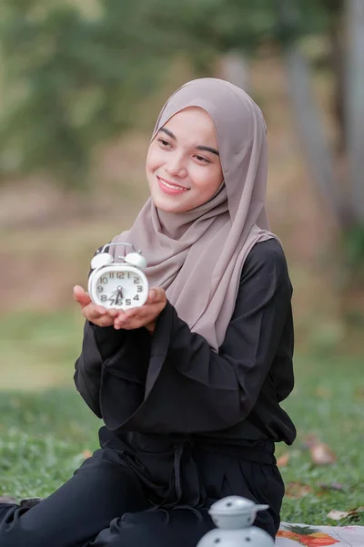 目覚まし時計を持ちながら微笑む若いアジア系ムスリム女性 — ストック写真