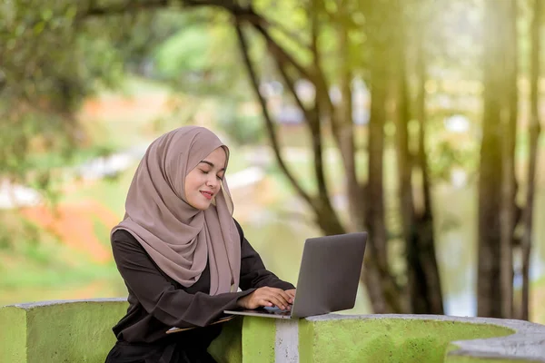 美しいイスラム女性の学生の写真20代は緑の公園に座っていると銀のラップトップを使用してスカーフを着て — ストック写真
