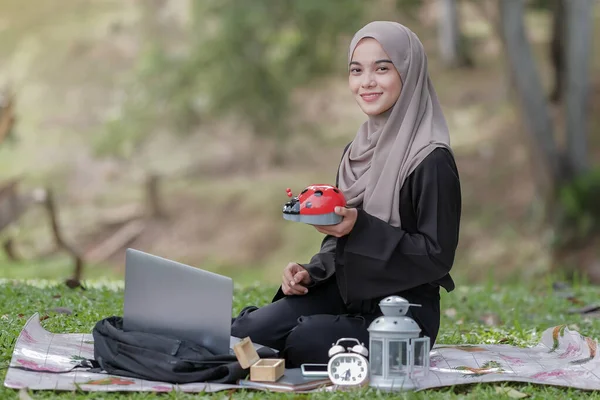 Красивая Молодая Женщина Хиджабом Зеленой Траве Парке Держащая Копилку Думать — стоковое фото