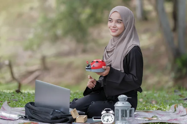 公園の緑の芝生の上にヒジャーブを持つ美しい若い女性は 貯金箱を持っています 私の将来を考え 簡単に救う — ストック写真