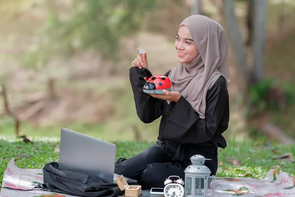 Bella Giovane Femmina Con Hijab Mettere Monete Salvadanaio Parco Concetto — Foto Stock