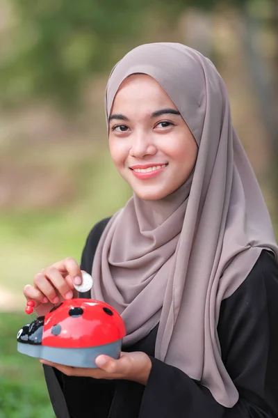 Wanita Muda Cantik Dengan Jilbab Menempatkan Koin Dalam Celengan Babi — Stok Foto