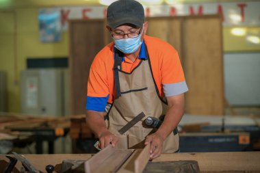 Odaklanmış profesyonel ahşap işçisinin elektronik yönlendirici kullanmasının ön görüntüsü. Ahşap ve marangozluk üretimi. Mobilya imalatı..