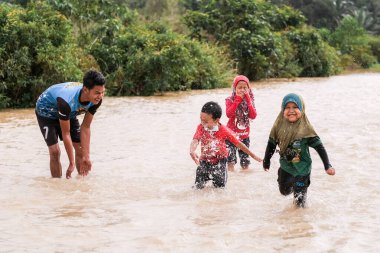 Pekan, Malezya - 12 Ocak 2021: Bir grup çocuk yolda sel sularında oynuyorlar.