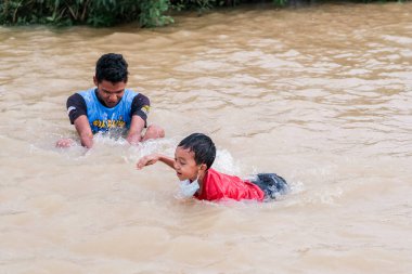 Pekan, Malezya - 12 Ocak 2021: Bir grup çocuk yolda sel sularında oynuyorlar.