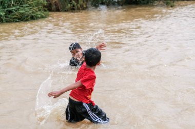 Pekan, Malezya - 12 Ocak 2021: Bir grup çocuk yolda sel sularında oynuyorlar.